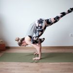 a woman doing a handstand on a yoga mat