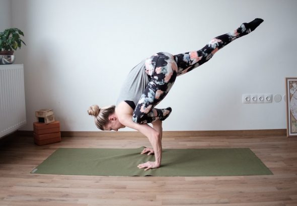 a woman doing a handstand on a yoga mat